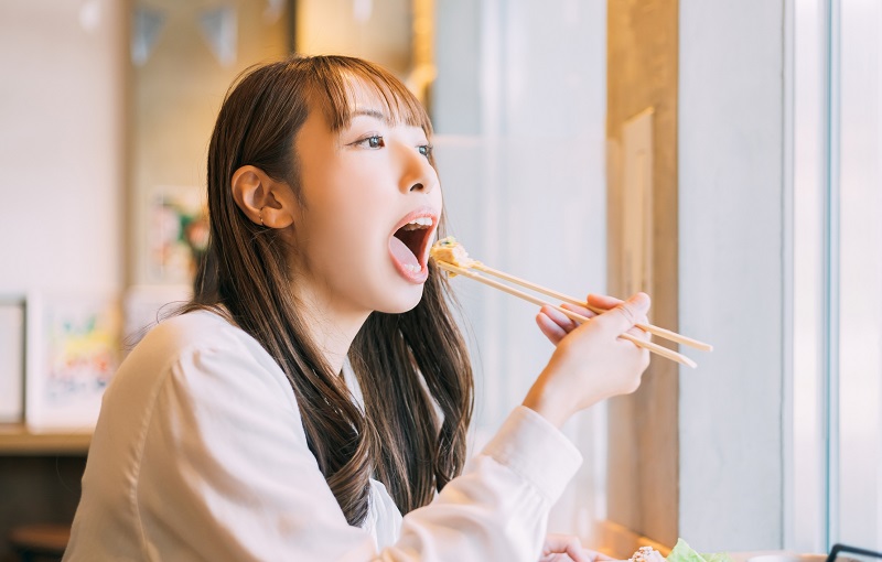 大きく口を開けて食事をしている女性の写真