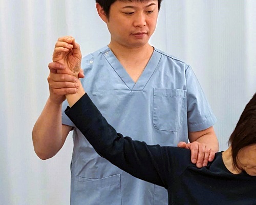 肩関節の検査をしている整体師の写真
